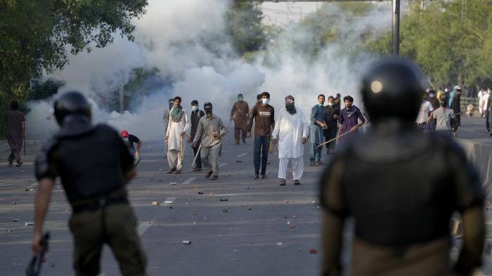Supporters of Pakistan's former Prime Minister Imran Khan throw stones after police fire tear gas to disperse them protesting against the arrest of Khan in Lahore, Pakistan.