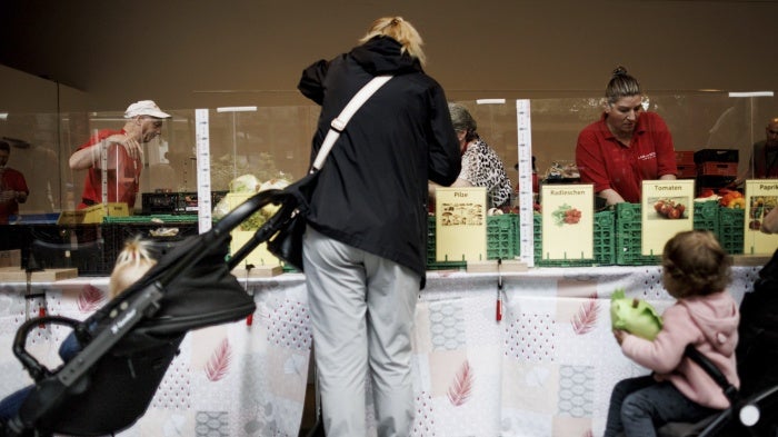 A woman at a food distribution center next to two strollers