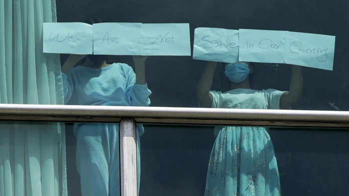 Migrants expelled from the US hold up papers that read “We are not safe in our country” in the window of a hotel