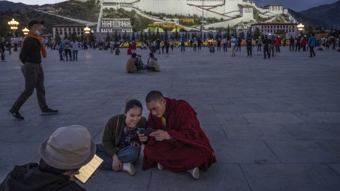 A Tibetan Buddhist monk and a woman share a mobile phone outside the Potala Palace in Lhasa, Tibet Autonomous Region, China, on June 1, 2021. 
