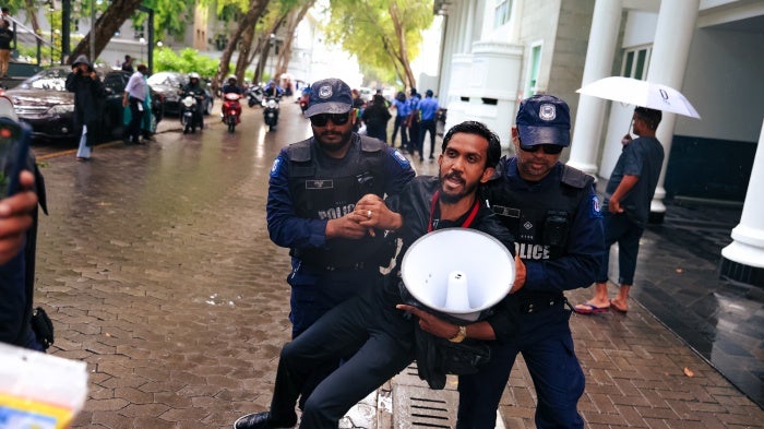 Maldives police detain a journalist during a protest against the Maldives Media and Broadcasting Regulation Bill outside government offices in the capital, Malé, on August 27, 2025.
