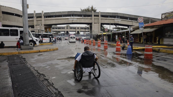 A wheelchair user searches for options to cross an under bridge while dredging work is carried out after a historic heavy rainfall in Mexico City, Mexico, on August 10, 2025.