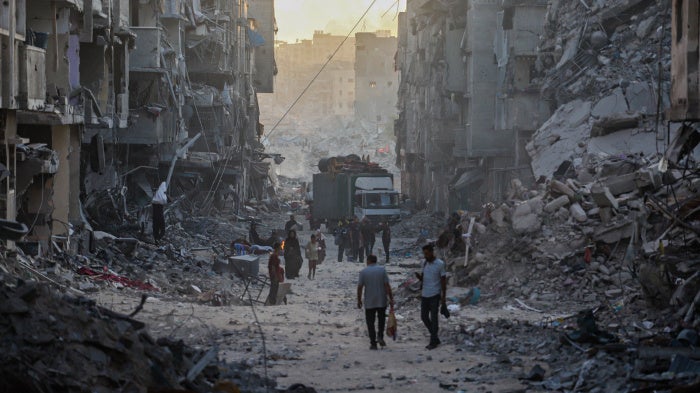 Palestinians walk through the rubble of residential buildings