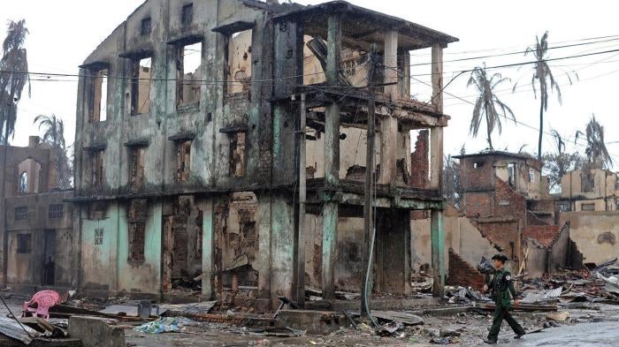 A Burmese soldier walks past a partially destroyed building in Sittwe, capital of Arakan State in western Burma, on June 14, 2012.