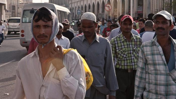 Migrant workers gather on “Bank Street,” in downtown Doha, where many workers wire remittance money to their families in their home countries. 