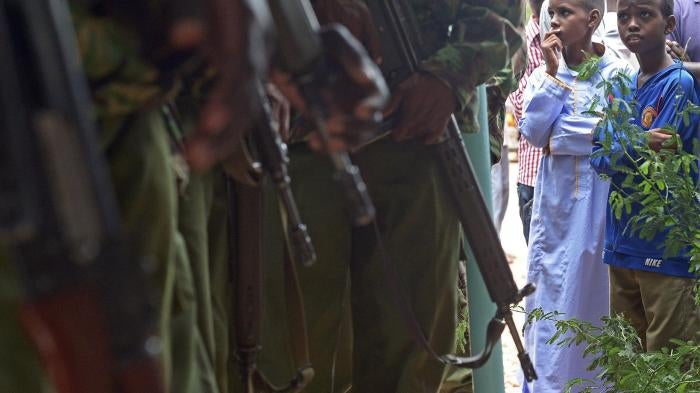 A picture of children looking at Kenyan police carrying guns.