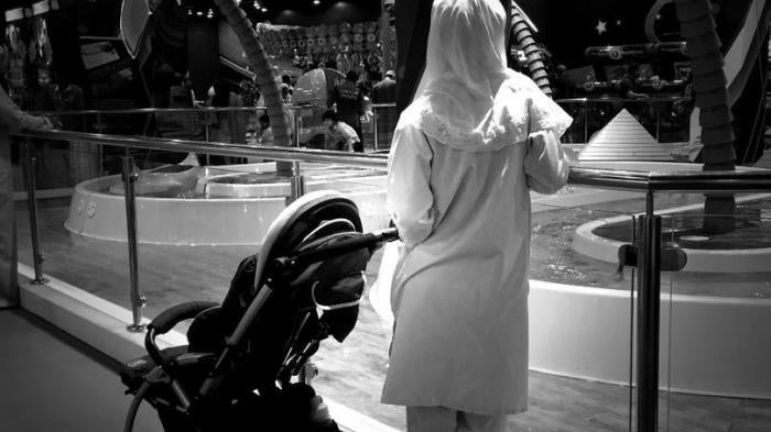 A migrant domestic worker watches over a child playing in the Magic Planet, City Centre Muscat, a shopping mall in Oman. 