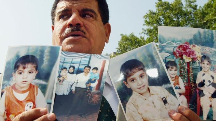 داود موسى، والد بهاء موسى الذي توفي في 2003 في عمر 26 عاما رهن الاحتجاز من قبل جنود بريطانيين في العراق، رافعا صور ابنه وصورة عائلية أمام وسائل الإعلام، بعدما وصوله إلى جلسة بمحكمة بريطانية في 28 يوليو/تموز 2004 حول انتهاكات حقوق الإنسان في العراق. © 2004