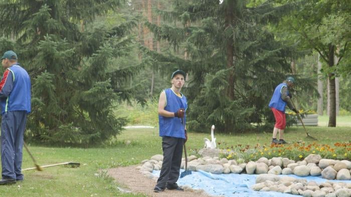 A young man does yard work on the grounds of a closed state institution for adults with disabilities.
