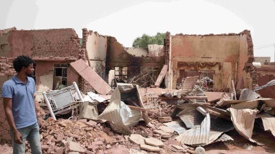 Man stands next to building destroyed during fighting in Khartoum, Sudan