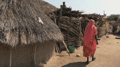 Woman walking besides huts.