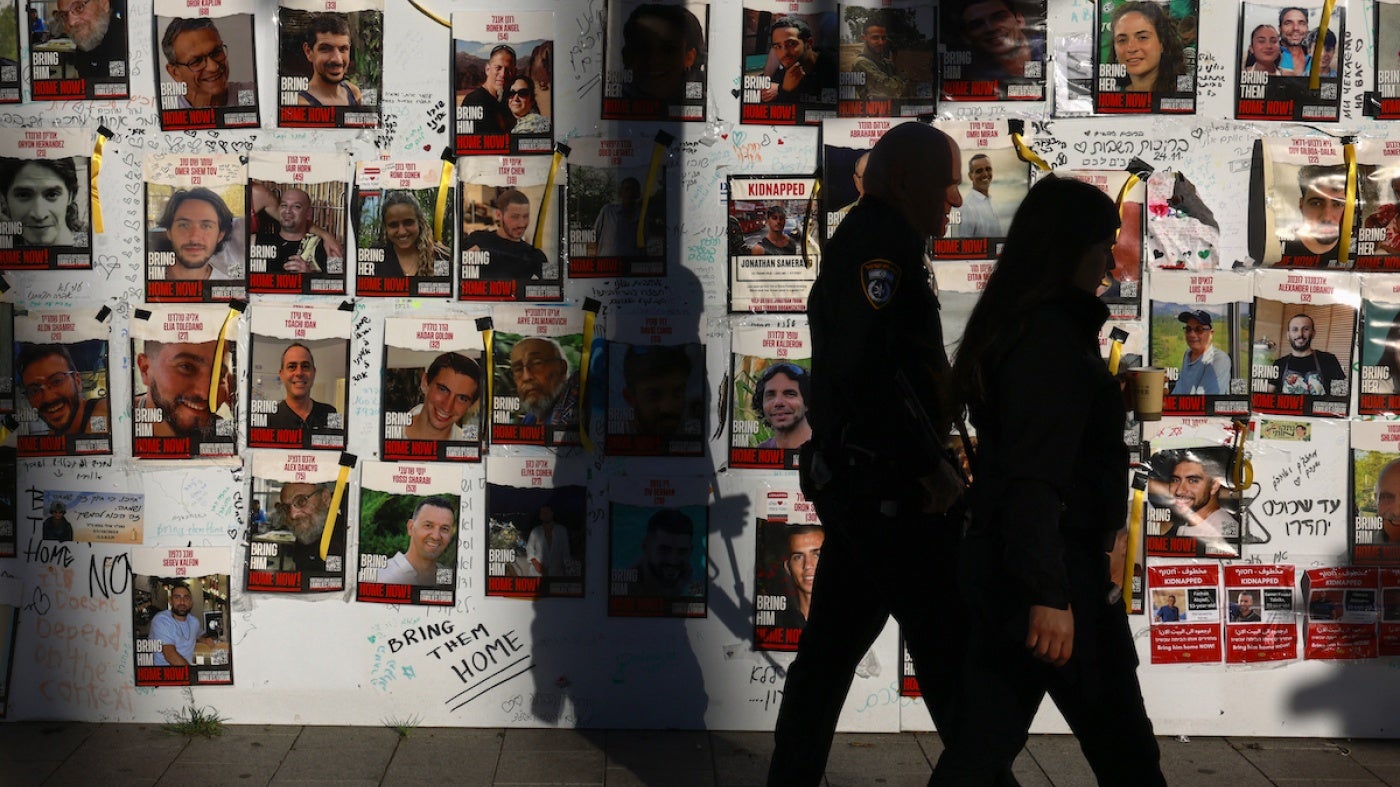 People pass by portraits of Israeli hostages from Israel held in Gaza since the October 7 attacks in Tel Aviv, December 17, 2023. 