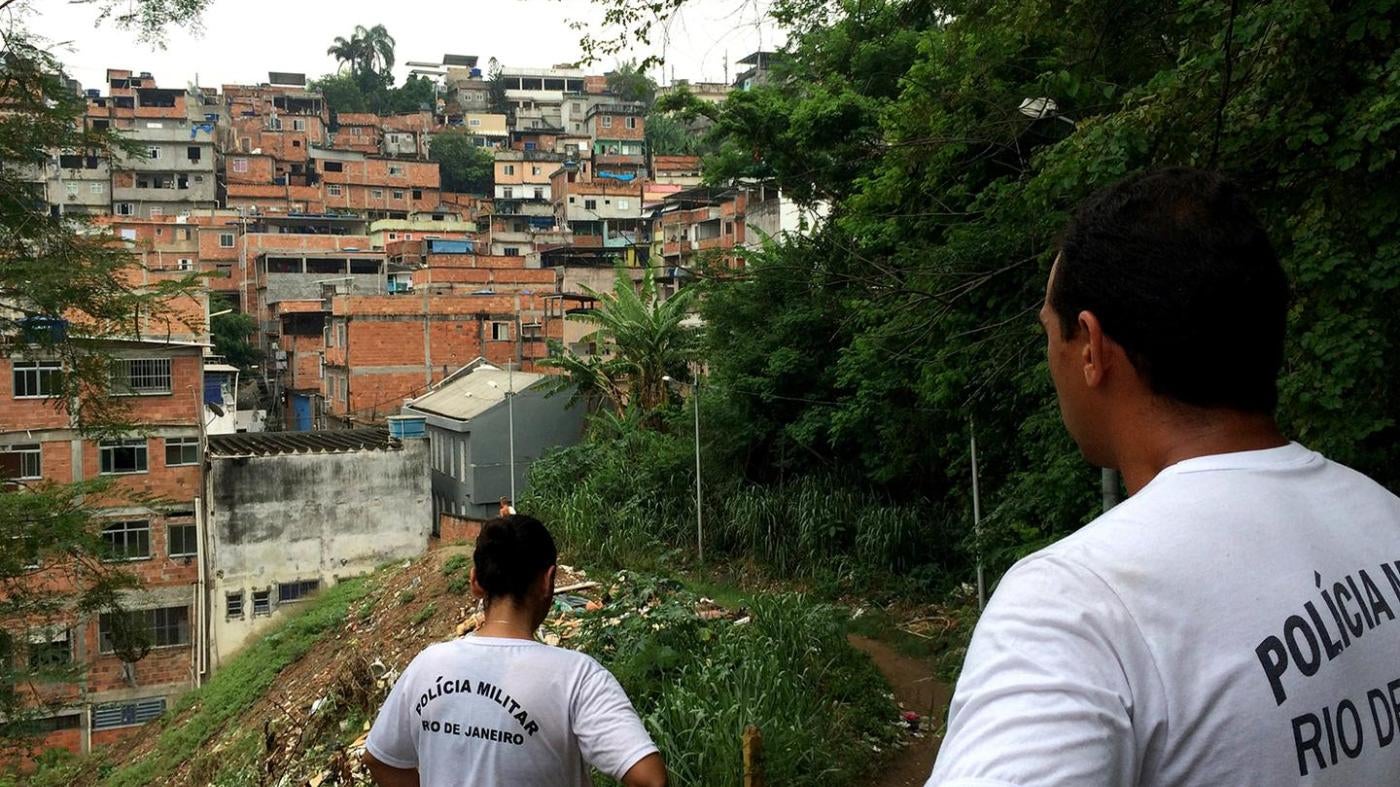 Military police officers Roberta Moreira and Wallace Justo walk through one of the trails at Mangueira favela on January 14, 2016. Members of the local Pacifying Police Unit (UPP), they carry out social projects with children to try to gain the