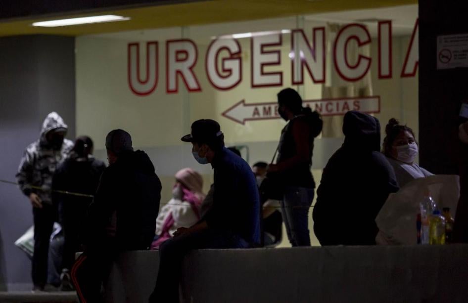 Varias personas que usan mascarillas y que afirman haber experimentado síntomas de Covid-19 esperan para hacerse la prueba fuera de una sala de urgencias.