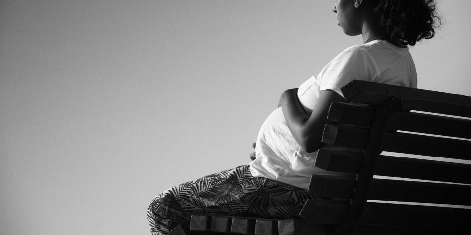 A pregnant African-American woman sits on a bench in a black and white photo
