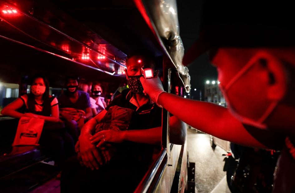 A police officer checks the temperatures of passengers inside a jeepney at a checkpoint in Manila, Philippines, March 16, 2020. 
