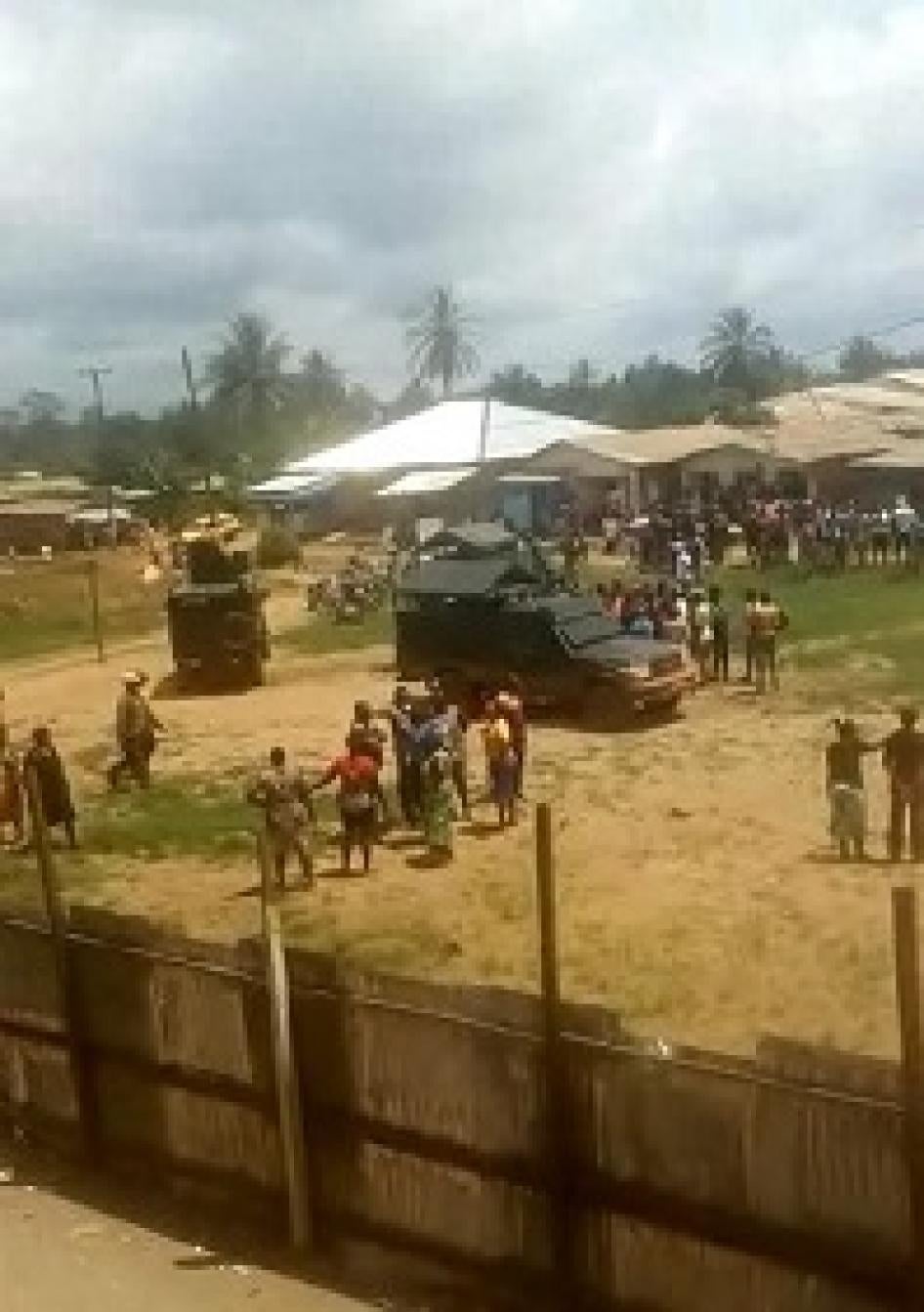 foule rassemblée à l'extérieur de l'école. véhicule de l'armée stationné.