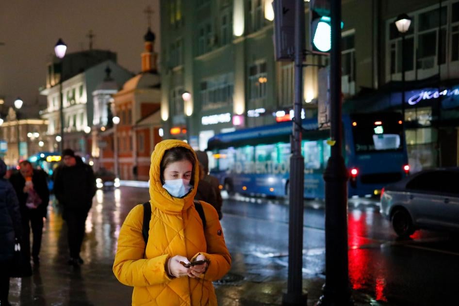 A woman wearing a face mask looks at her smartphone as she walks through a street in Moscow, Russia, November 23, 2020. 