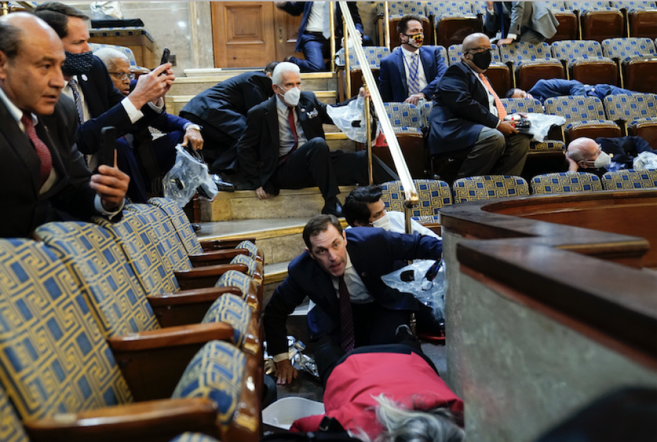 People shelter in the House gallery as protesters try to break into the House Chamber at the U.S. Capitol on Wednesday, Jan. 6, 2021, in Washington.