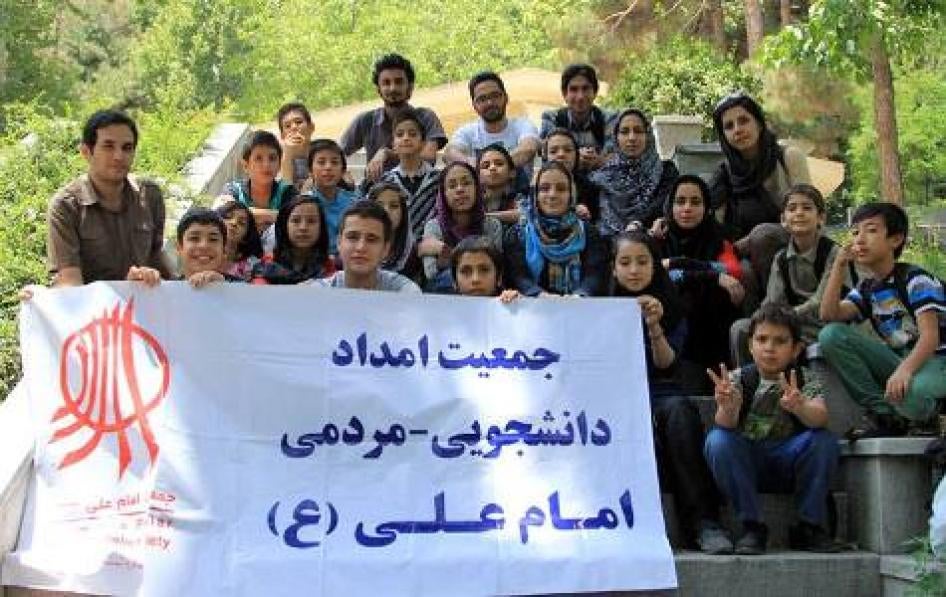 اعضای یکی از خانه‌های درمان جمعیت امام علی بنری با اسم و آرم انجمن در دست گرفته اند.  