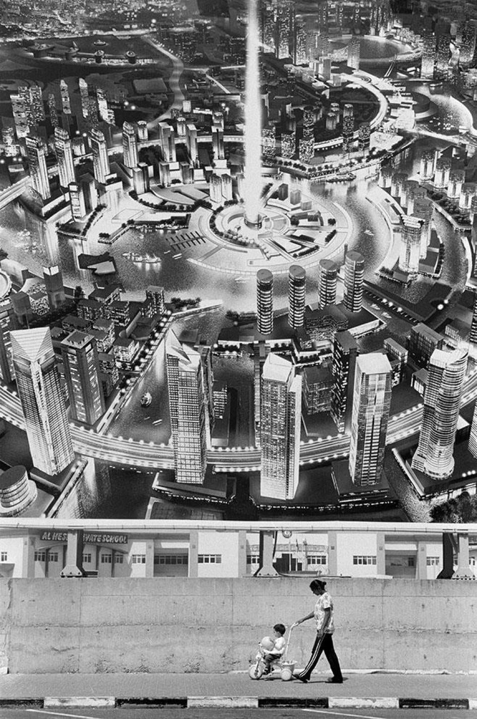 عاملة منزلية مع طفل تمر تحت لافتة إعلانية في الإمارات. 