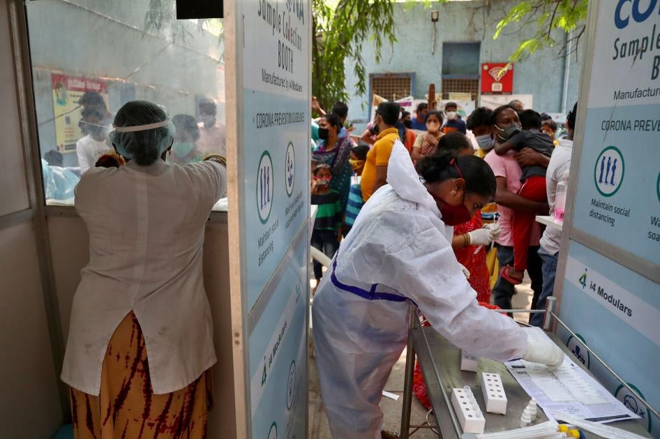 People wait to get tested for Covid-19 in Hyderabad, India. A crowd stands before two health care workers. 