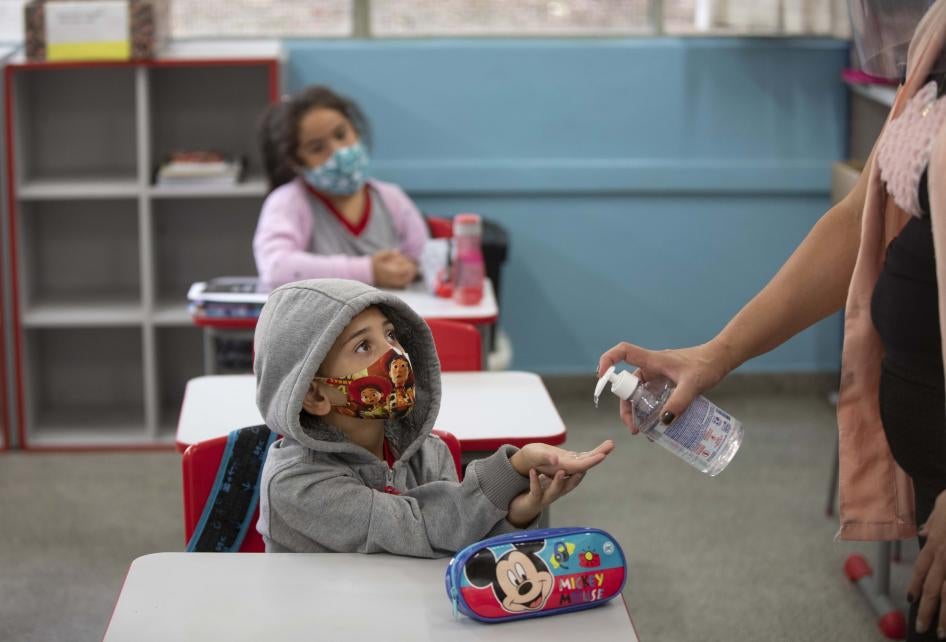 Um aluno recebe alcool em gel nas mãos em escola pública de São Paulo no primeiro dia de aula presencial, em 8 de fevereiro de 2021.