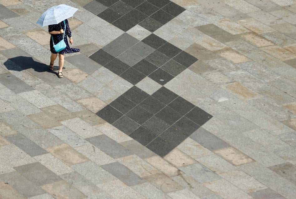 A woman shields herself from the sun with an umbrella on a hot summer day in Cologne, Germany, July 25, 2019. 