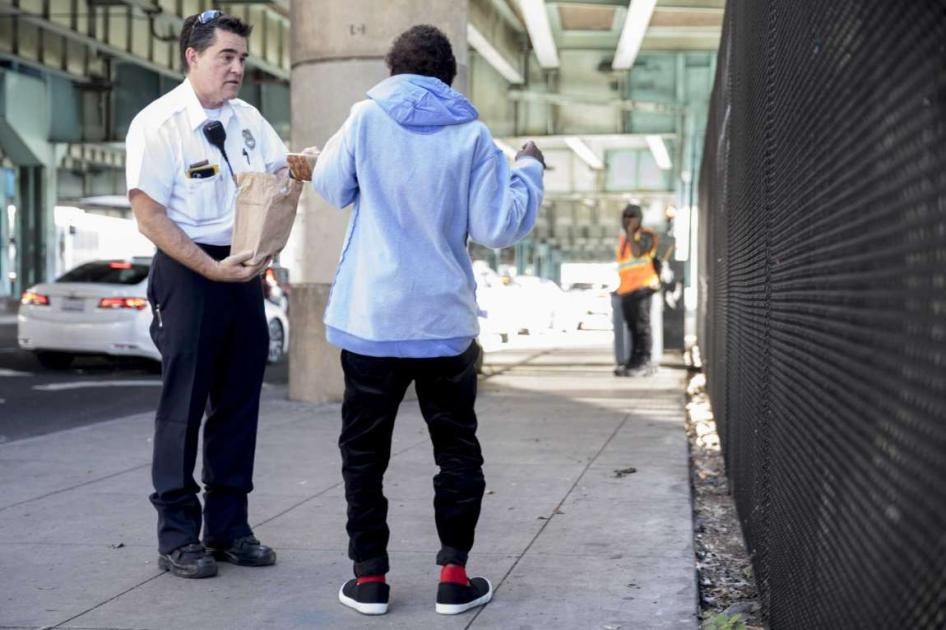 A worker offers food to a homeless woman while escorting her into S.F.’s Division Navigation Center in January 2020.