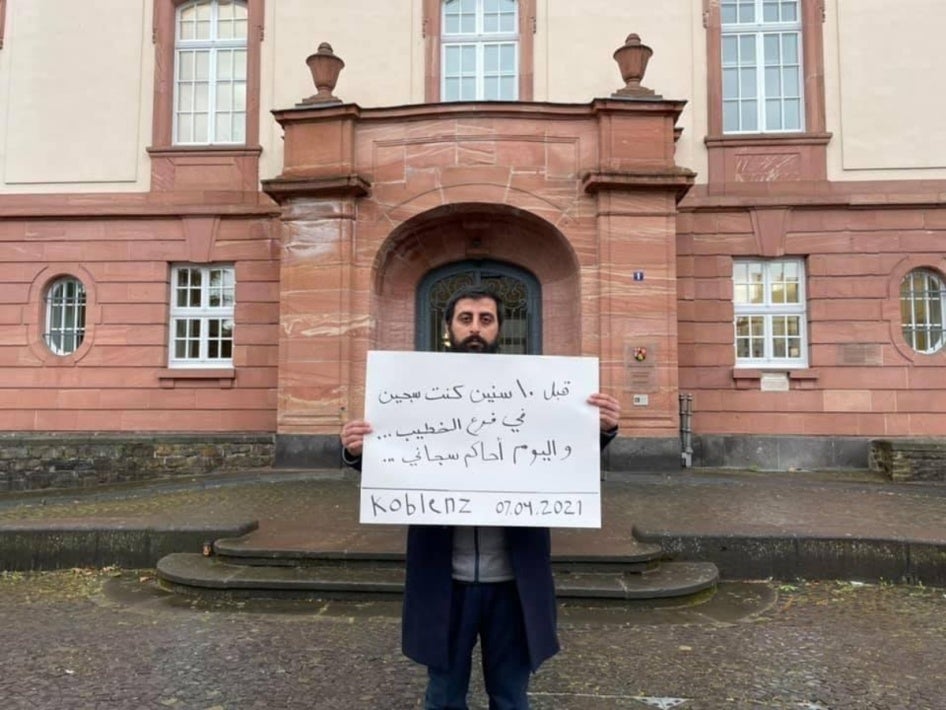 Amer Matar, devant le tribunal de Coblence le 7 avril 2021, tenait une affiche avec ce message en arabe : « J’ai été emprisonné à la section al-Khatib et aujourd’hui, j’observe le procès de mon bourreau ».