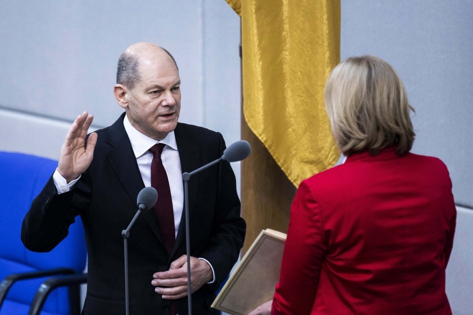 A man wearing a suit raises his right hand