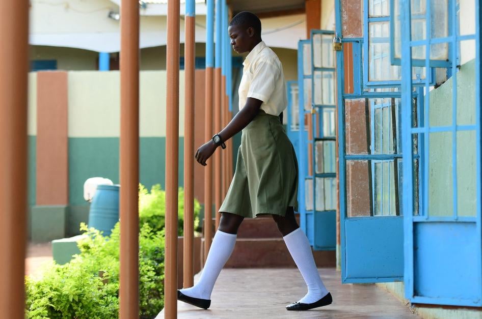 A female student wearing a school uniform walks out of a building