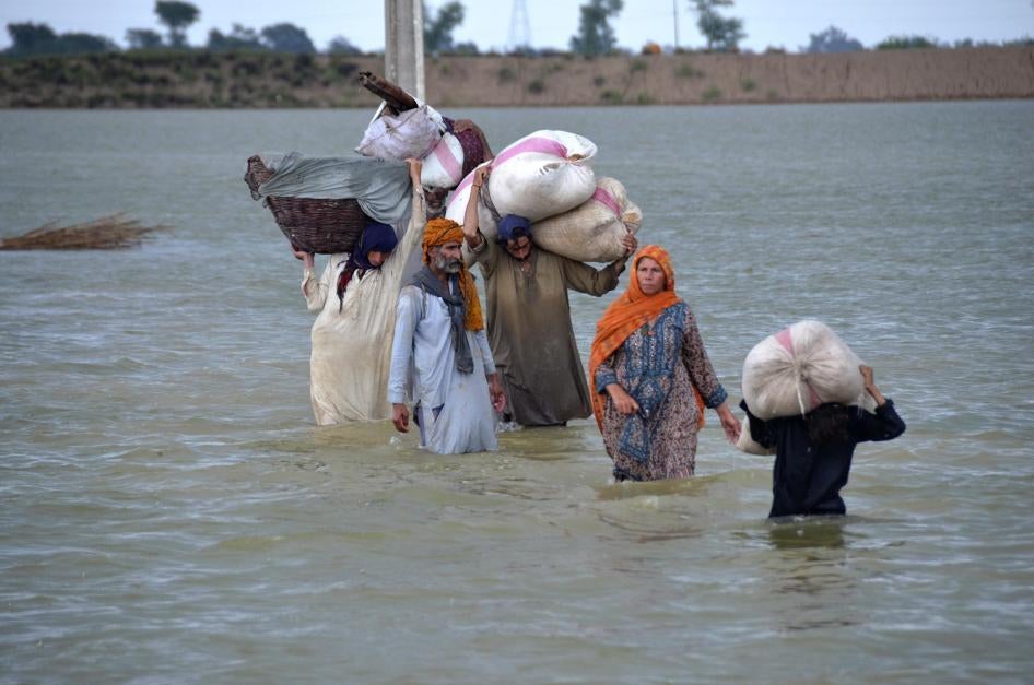 A displaced family wades through a flooded area in Jaffarabad