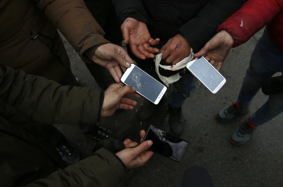 Migrants show broken phones in the village of Horgos, Serbia