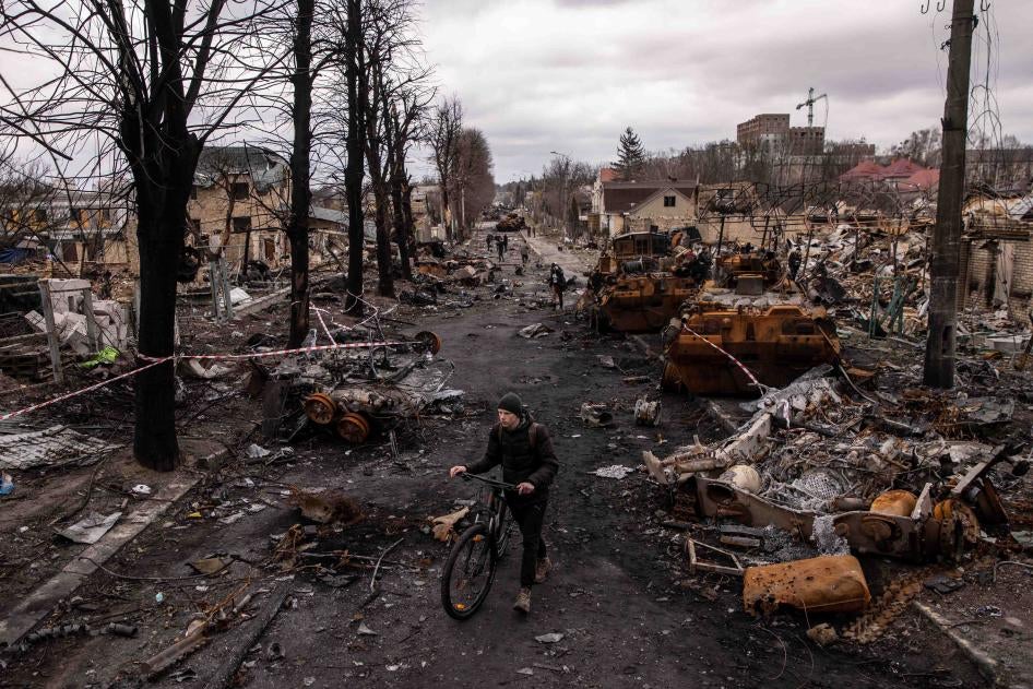 A man pushes his bike through debris and destroyed military vehicles