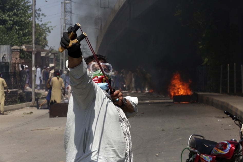 A protester aims a slingshot towards police (unseen)
