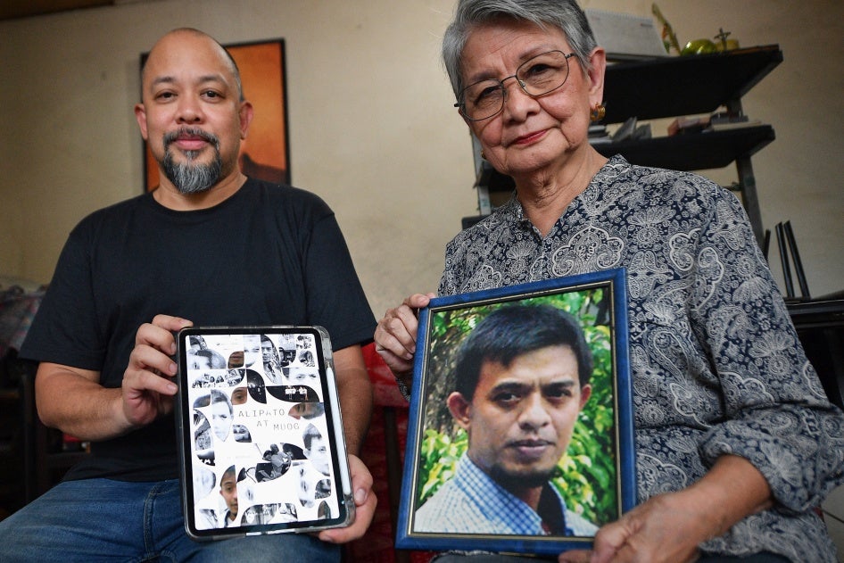 Edita Burgos (R) holds a portrait of her missing son, Jonas Burgos, while posing with her younger son JL Burgos, who directed the film “Alipato at Muog," a documentary about Jonas’ forced disappearance, Cinemalaya Film Festival, Pasay, Philippines, August 1, 2024. 