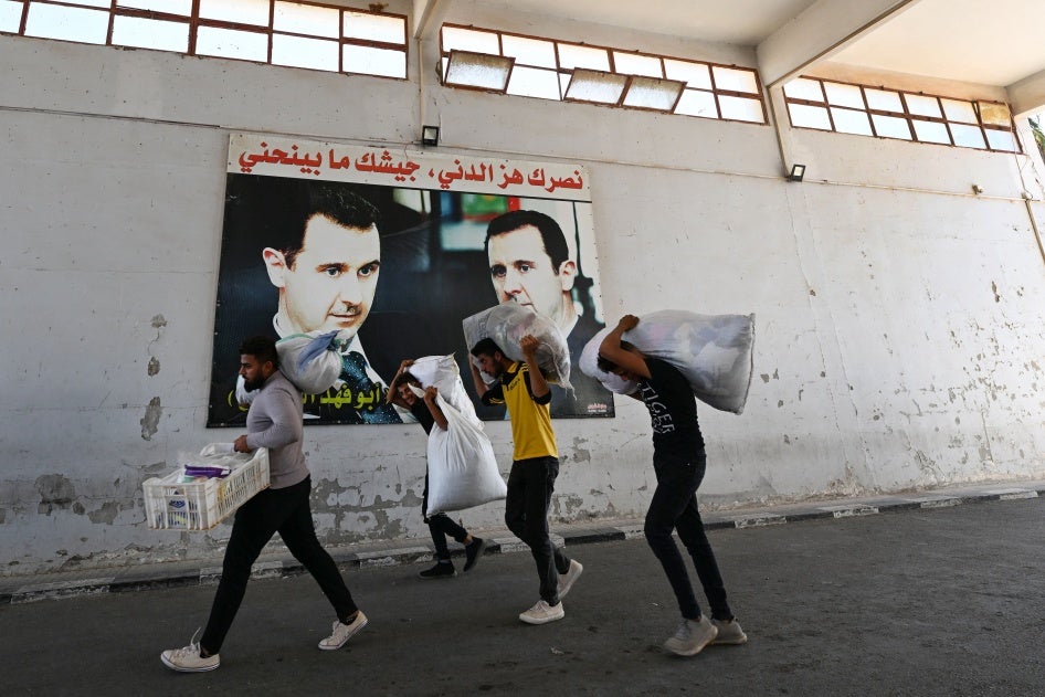Displaced people walk past posters of President Bashar al-Assad as they enter Syria from Lebanon via the Jusiyeh Border crossing, on October 2, 2024. 