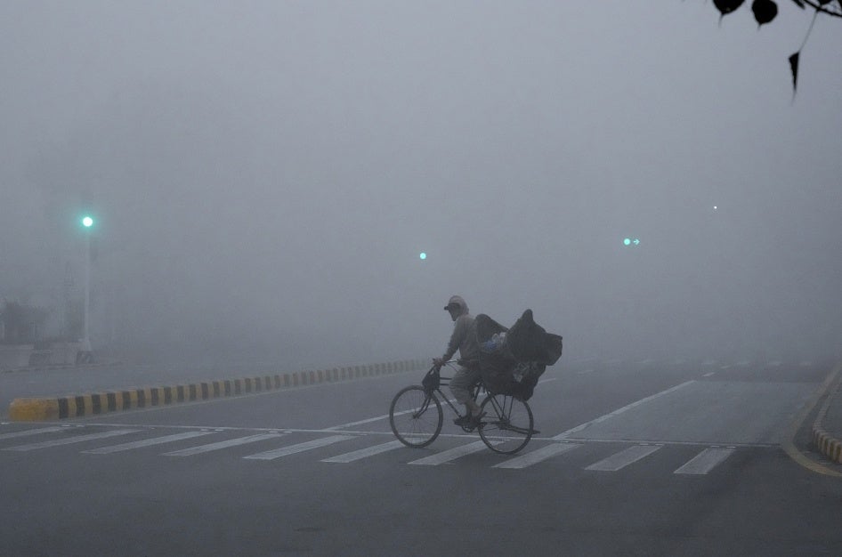 A cyclist crossing a road amid intense smog