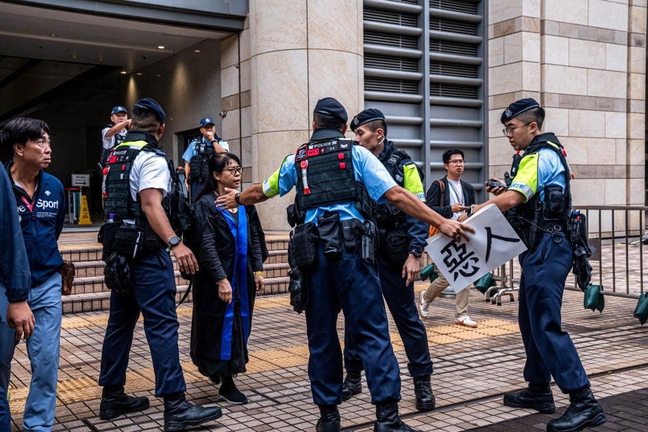 Police remove a sign from Elsa Wu, foster mother of activist Hendrick Lui