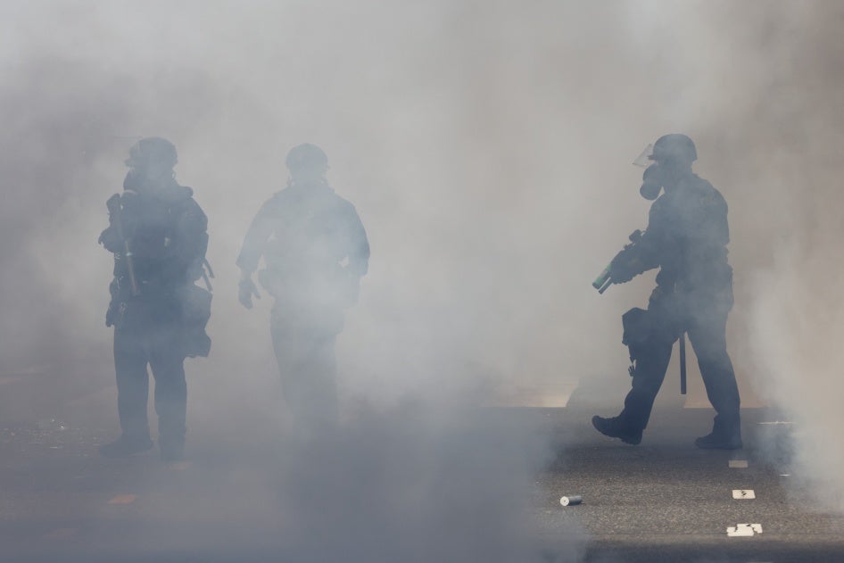 Police officers walk through tear gas after dispersing a crowd on N. Main St. during the "No Kings" protest in downtown Los Angeles on June 14, 2025.