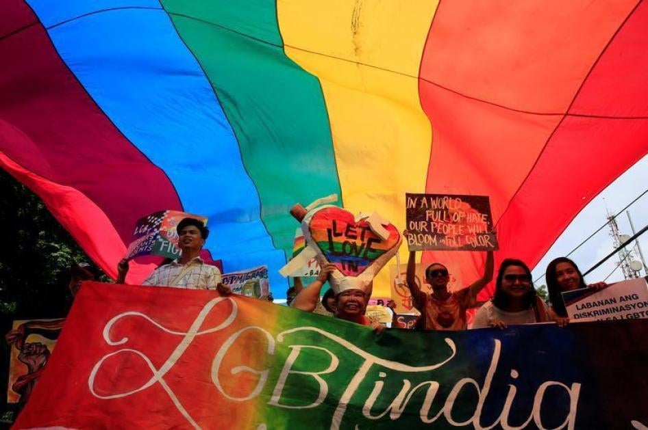 Supporters hold placards while marching under a rainbow flag during a LGBT Pride parade in metro Manila, Philippines June 25, 2016. 