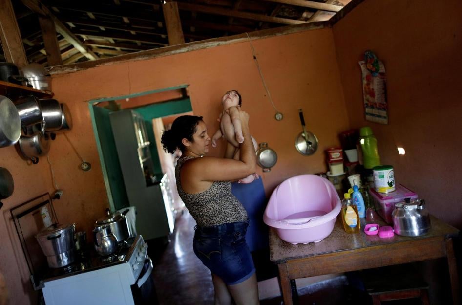 Raquel bathes her daughter Heloisa, a girl with Zika syndrome born in April 2016. Raquel says she cannot afford the medicines her twin daughters need for convulsions. 
