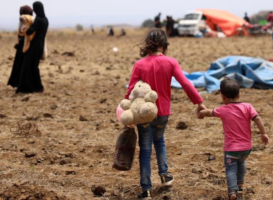 An Internally displaced girl from Daraa province carries a stuffed toy and holds the hand of child near the Israeli-occupied Golan Heights in Quneitra, Syria June 29, 2018. © 2018 Reuters/Alaa Al-Faqir