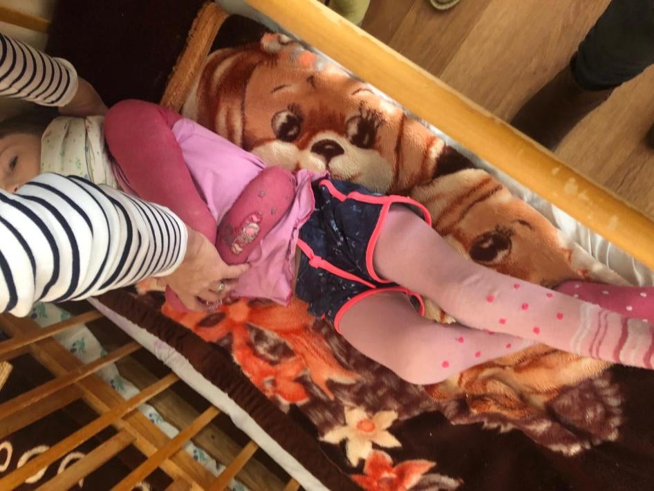 Девочка, чьи руки были связаны за ее спиной, в интернате для детей с инвалидностью.