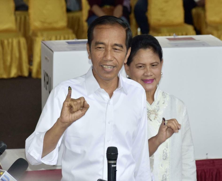 Presiden Indonesia Joko Widodo dan istrinya, Iriana, memamerkan jari-jari mereka yang bertanda tinta setelah memberikan suara dalam pemilihan presiden di sebuah TPS di Jakarta pada 17 April 2019.