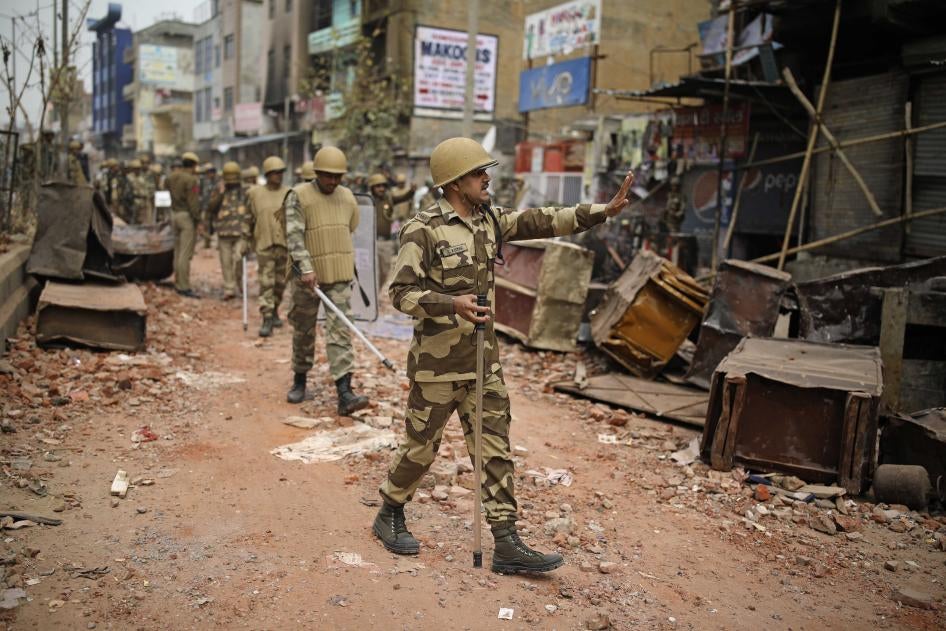 An Indian paramilitary soldier asks residents to stay indoors as they patrol a street vandalized in February 25th's violence in New Delhi, India, February 27, 2020.