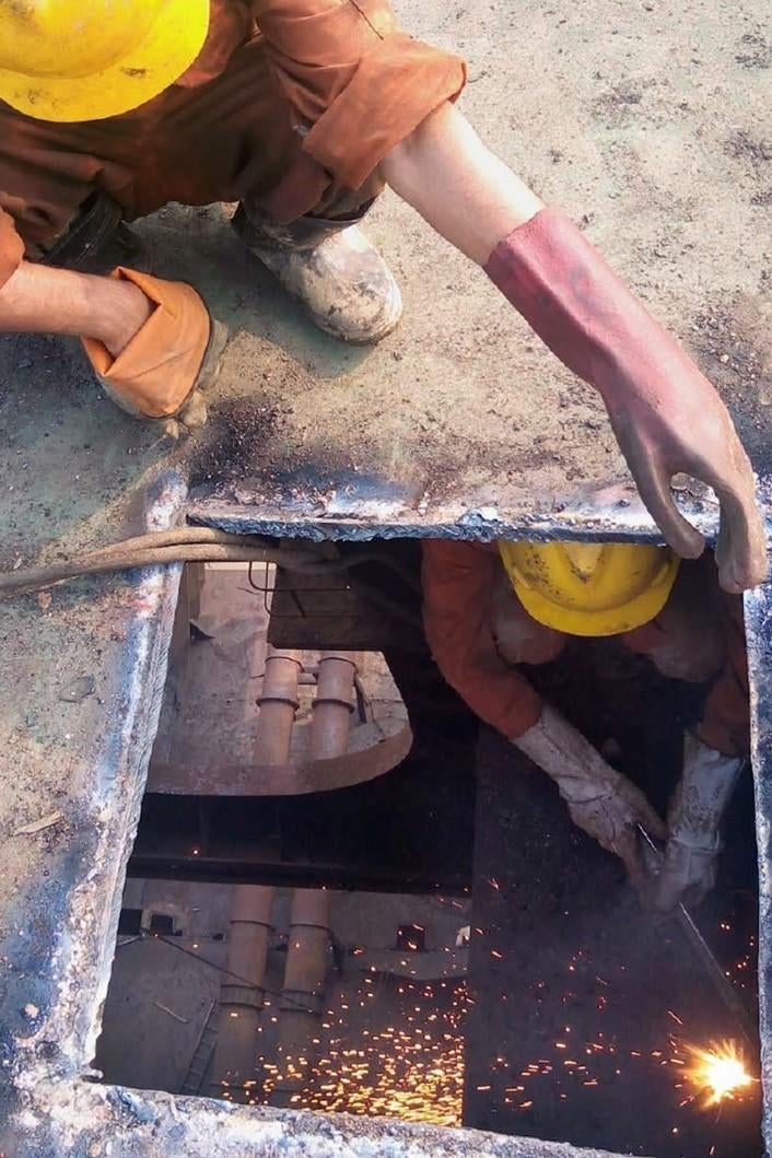 Shipbreaking workers cut through steel inside a confined space