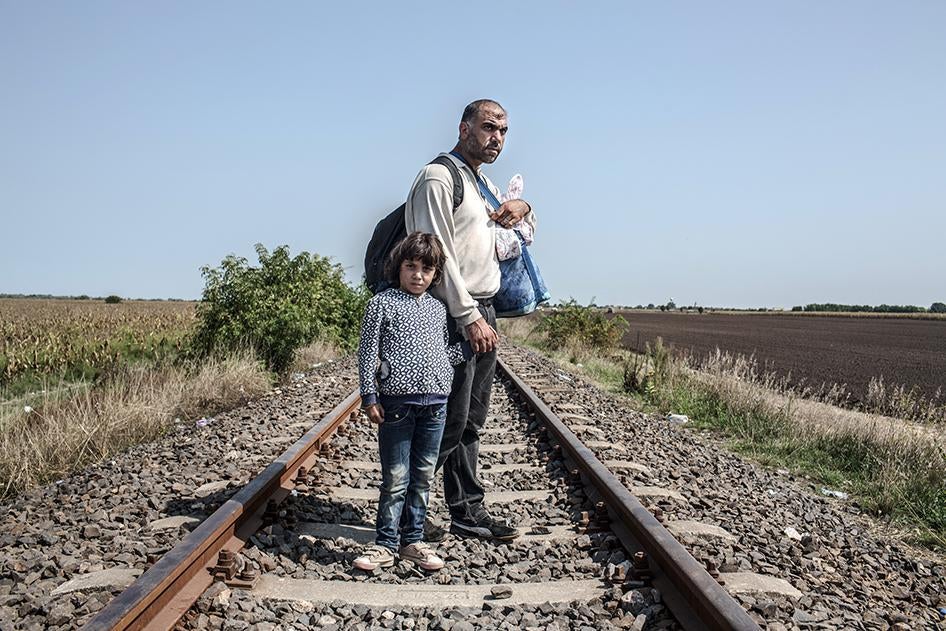 Syrian refugees, Hassan, 35, and his daughter Tasneem, 5, stand on train tracks in Hungary after crossing the border with Serbia on September 3, 2015. 