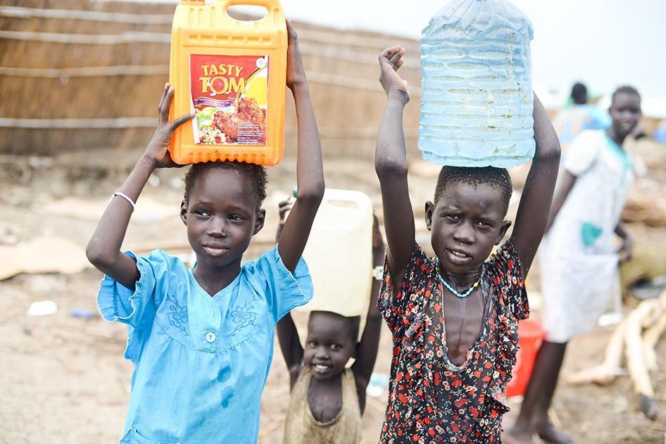 Girls carrying water to their shelters in the UNMISS camp near Bentiu. In some areas of the camp, women and girls have stopped coming to collect water before 7 a.m. because of the risk of sexual violence. 